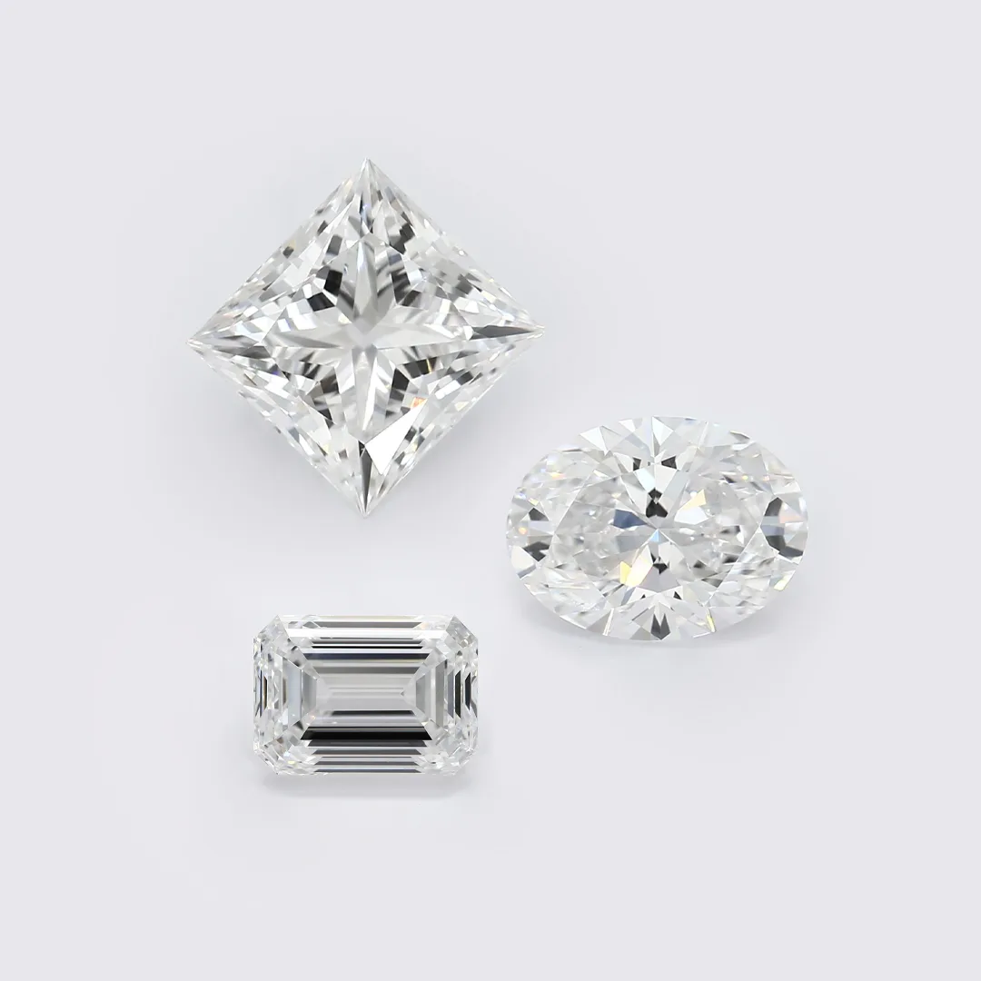 Three faceted lab-grown diamonds in princess, oval, and emerald shapes