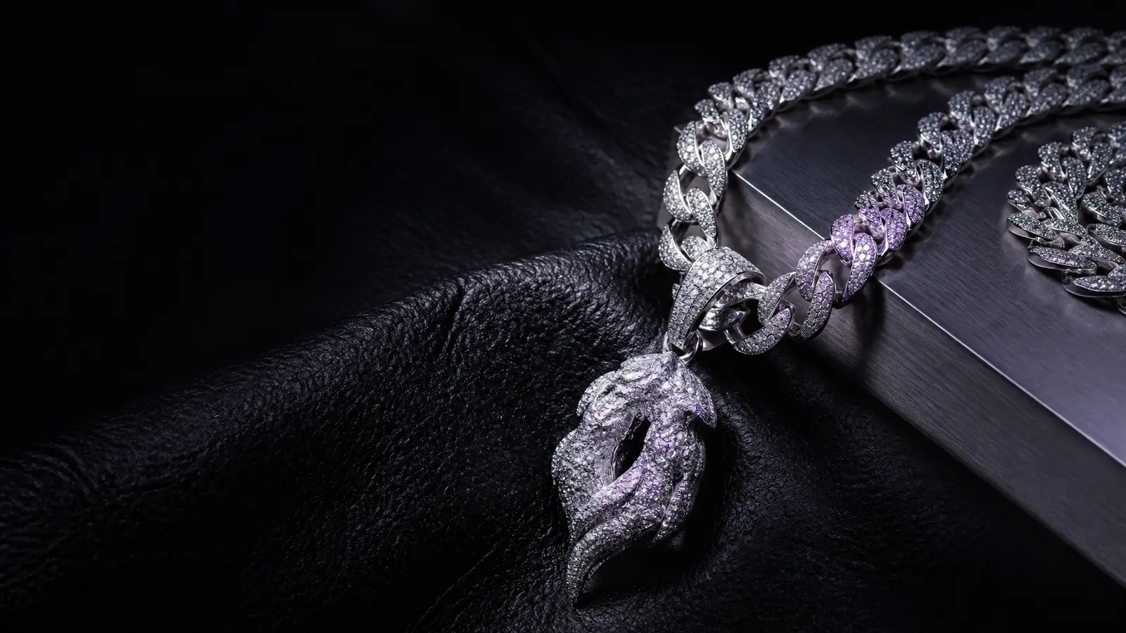 Iced-out silver Cuban link chain with a custom pendant on black leather